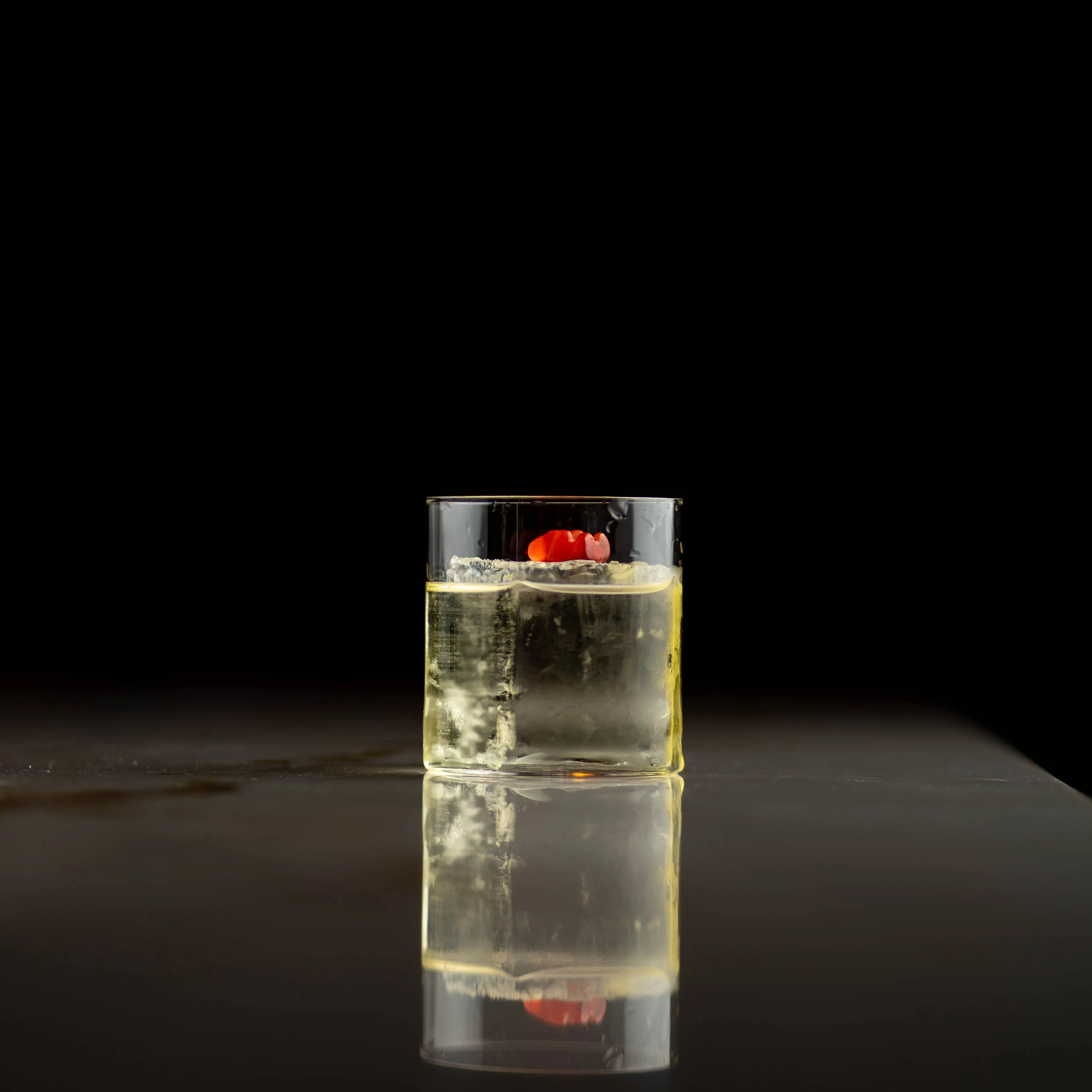 Highball med is og rød pynt mot svart bakgrunn