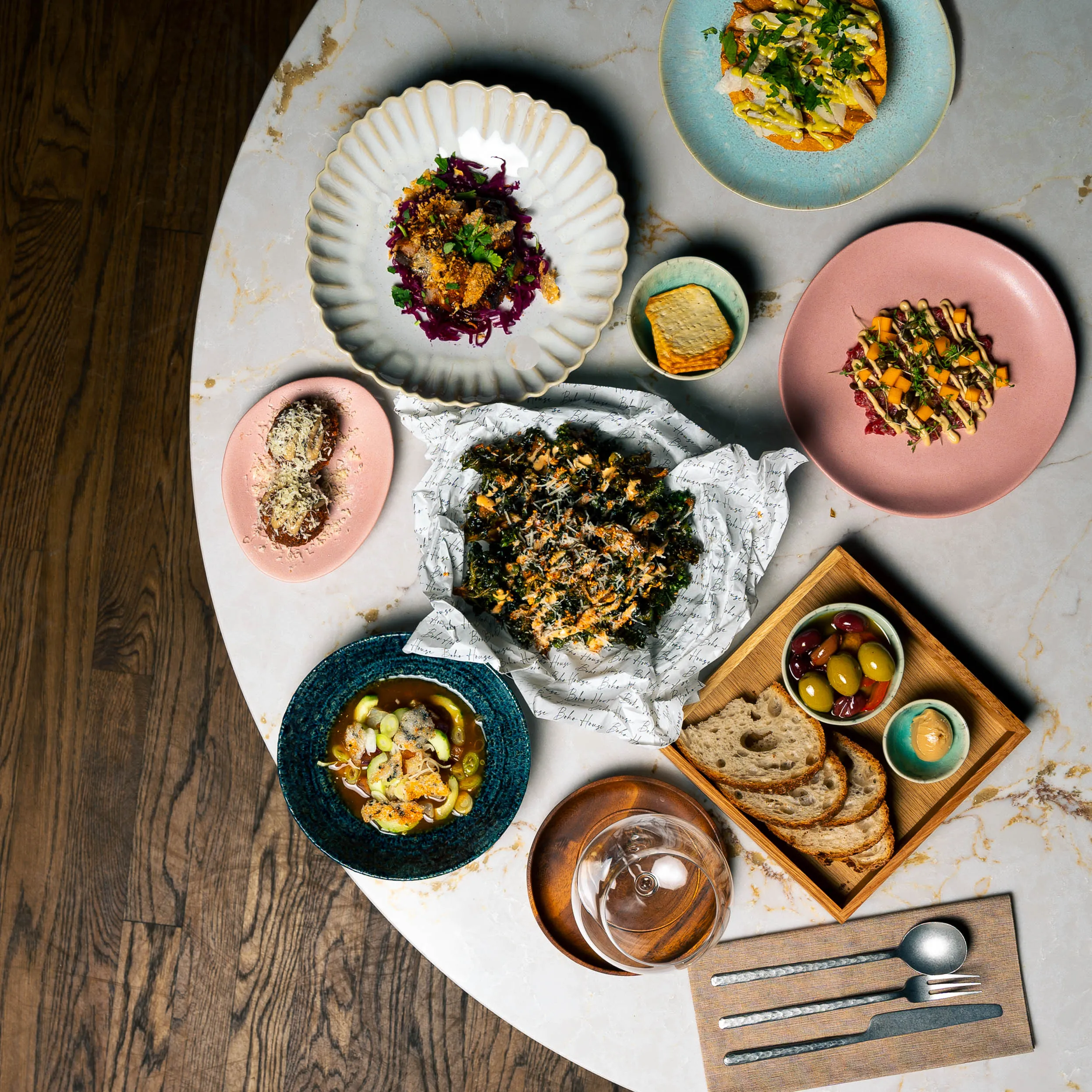 Bord sett ovenfra med mange små retter, brød og oliven