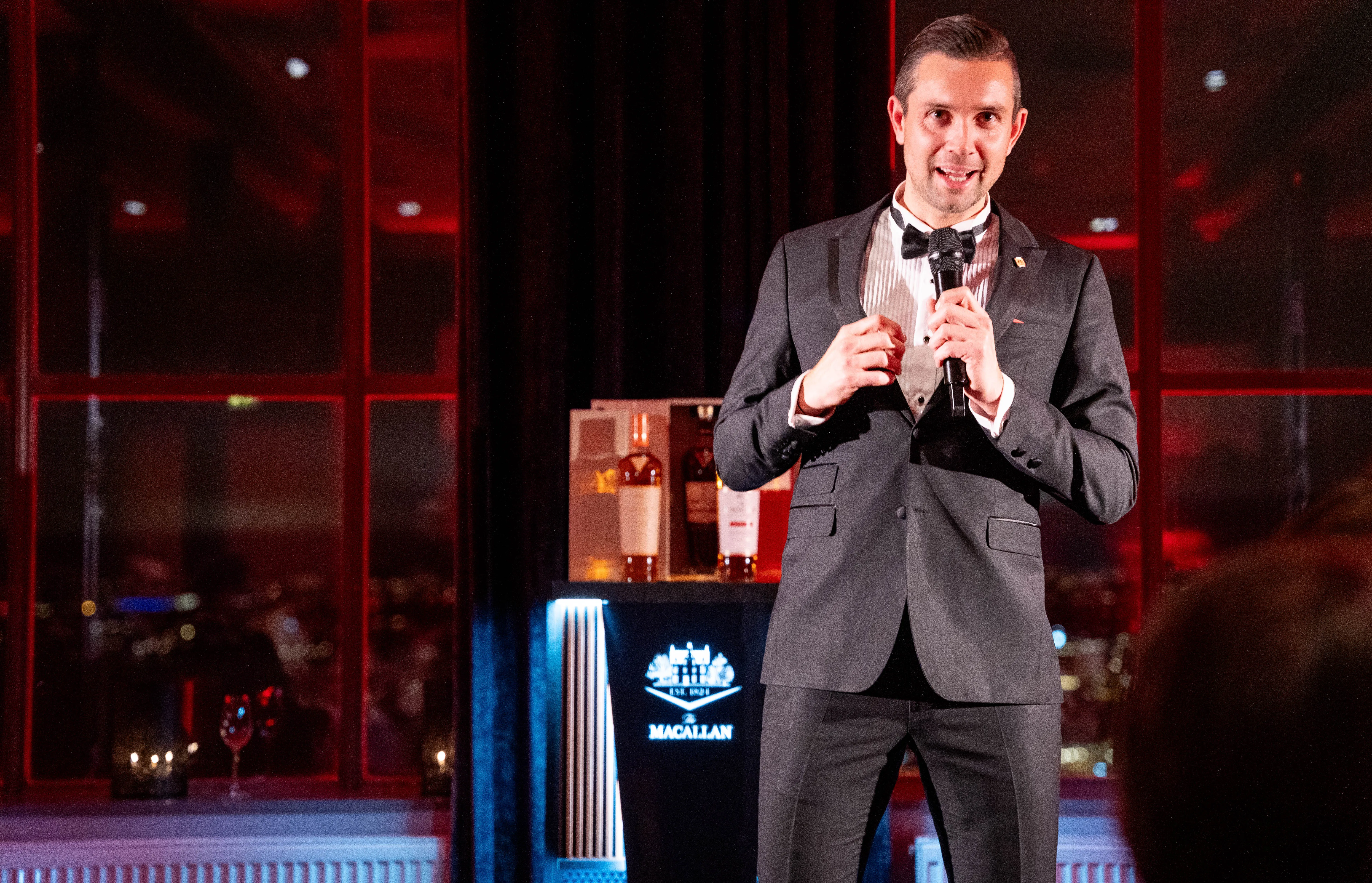 Mann med mikrofon foran The Macallan-montren i rødt lys