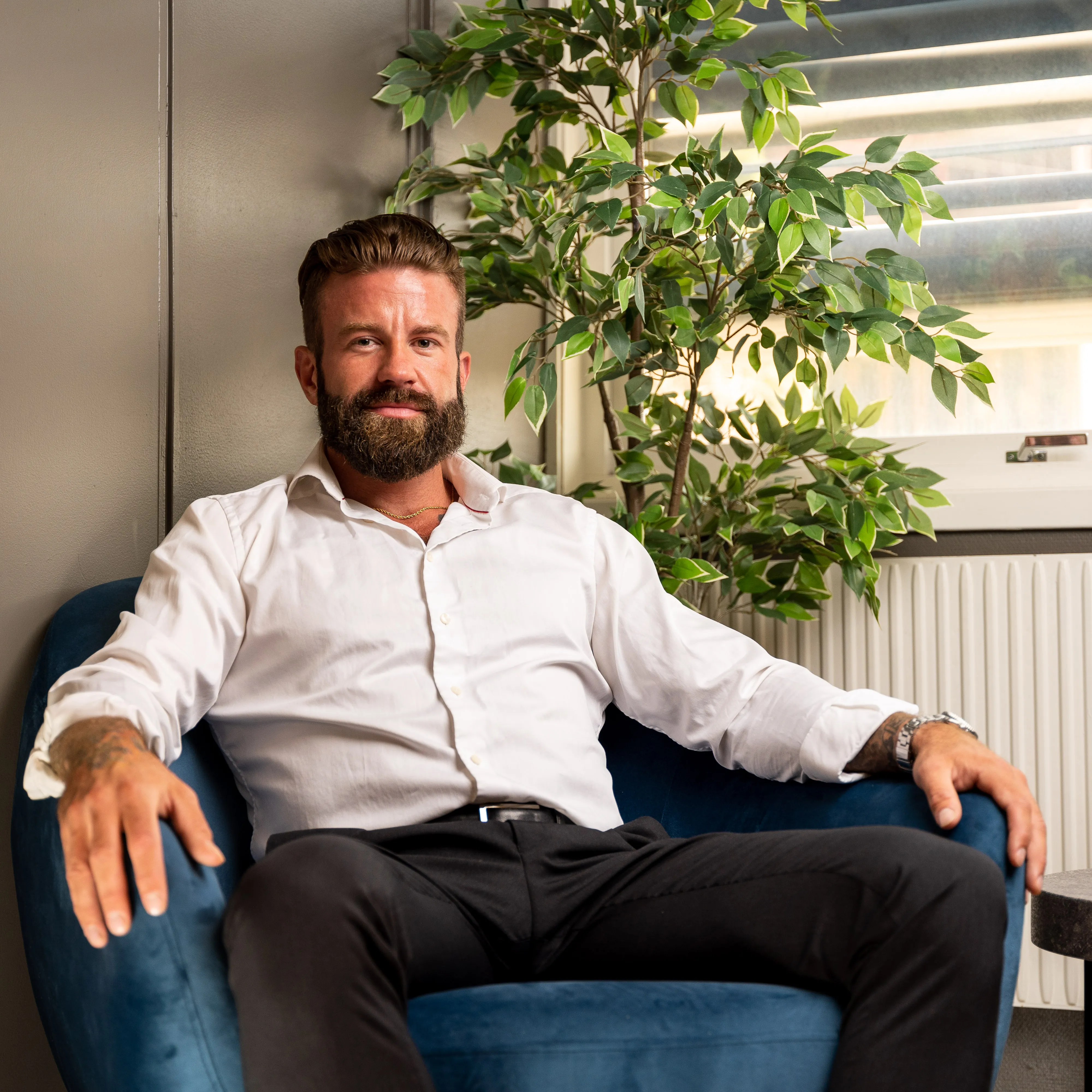 Aleksander Stormskjold sitter i en blå lenestol ved et vindu