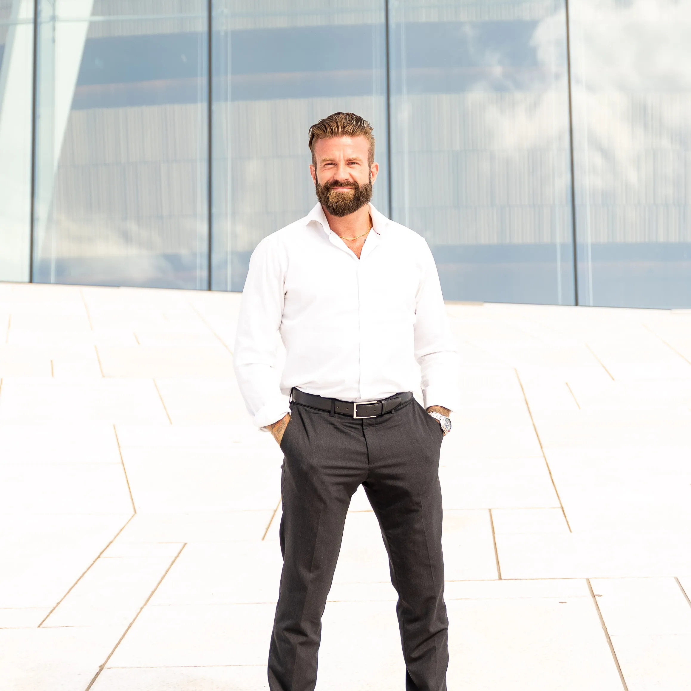 Aleksander Stormskjold står i hvit skjorte på en lys plass